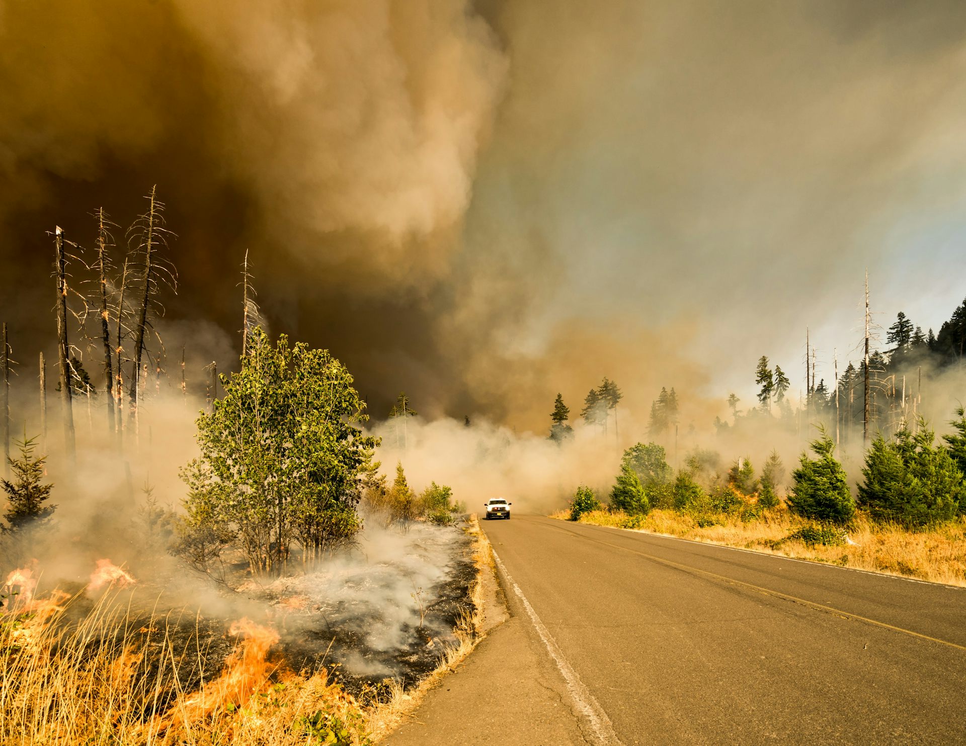 A car driving away from smoke from a forest fire