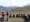 a group of outdoor enthusiasts sitting in a circle in an alpine meadow, listening to two instructors