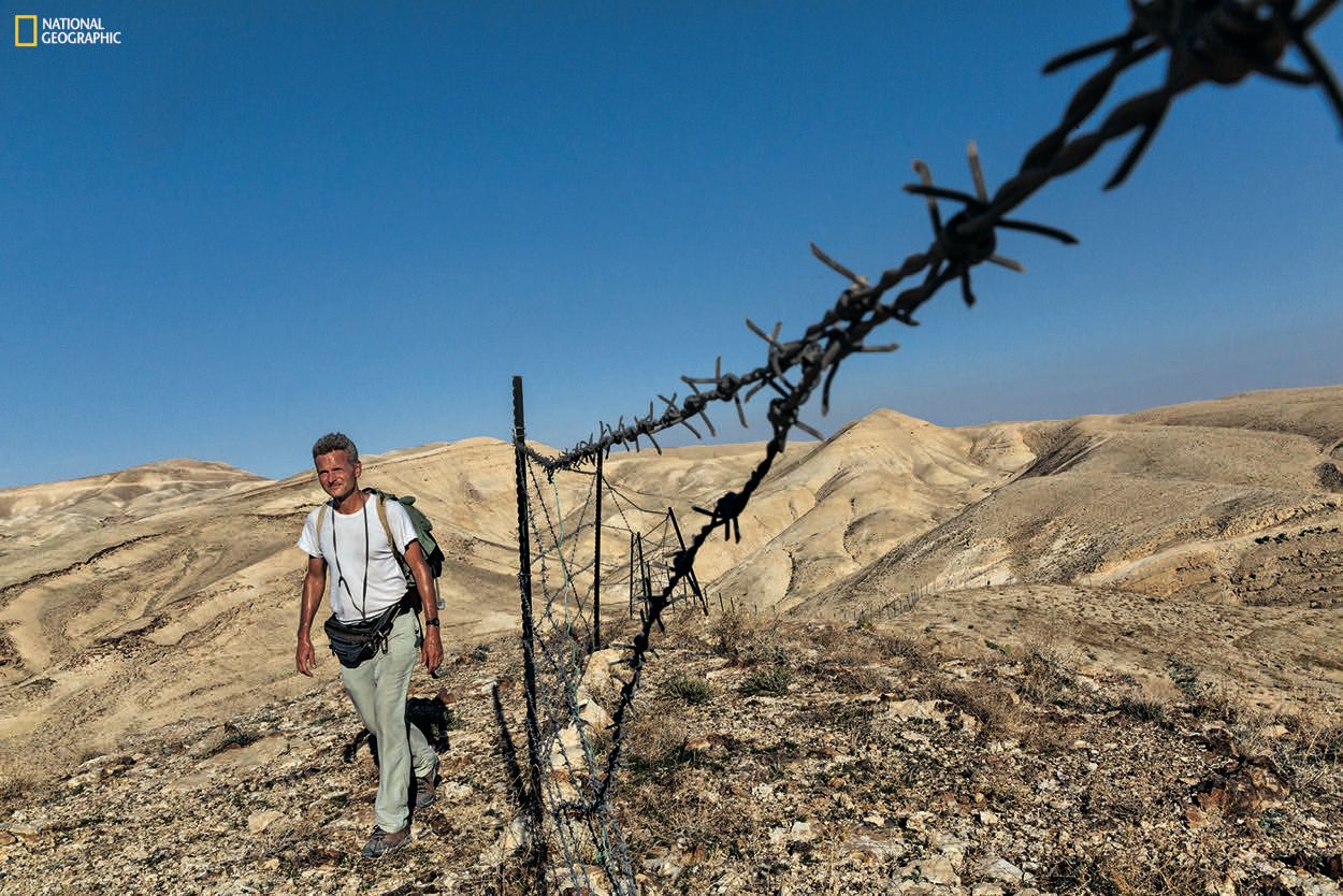 Striding toward Bethlehem, in the West Bank, Salopek is detoured by a herder’s tattered fence, one of the first human-made barriers—other than checkpoints and border gates—he’s faced in some 2,300 miles since he started out in Ethiopia. Join the journey at outofedenwalk.org.Photograph by John Stanmeyer / National Geographic