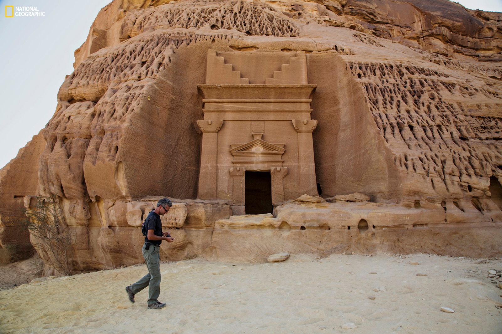 Paul Salopek wanders through the ancient Nabataean ruins of Madain Salih, carved into sandstone outcrops some 2,000 years ago. These structures were used as tombs for the wealthy during the Nabataean era. The kingdom stretched from its capital Petra in Jordan south to Madain Salih in the Hejaz region of present-day Saudi Arabia. Photo shows a tomb façade in the Al Khuraymat area of Madain Salih. Join the journey at outofedenwalk.org.Photograph by John Stanmeyer / National Geographic