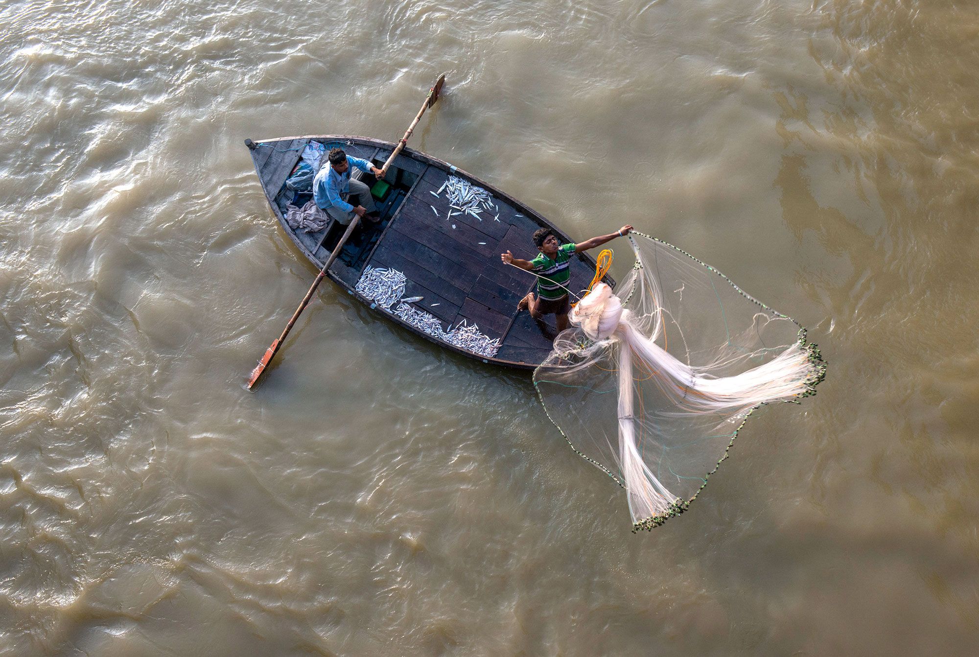 Above Kanpur, India, fishermen test their luck below an irrigation / flood weir. Most regions of the Ganges forbide fishing in its sacred waters but a Muslim community in the Kanpur region, see the river as an economic oppurtunity despite tails of toxic waters.